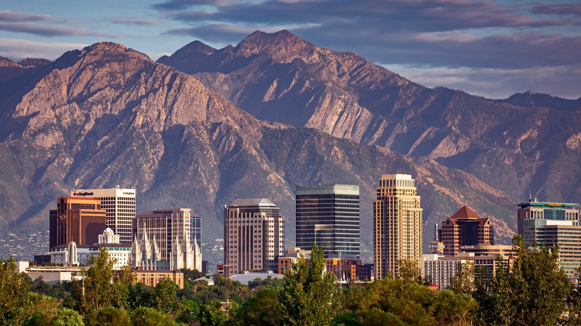 The downtown Salt Lake City skyline at golden hour, backed by the peaks of the Wasatch Range.